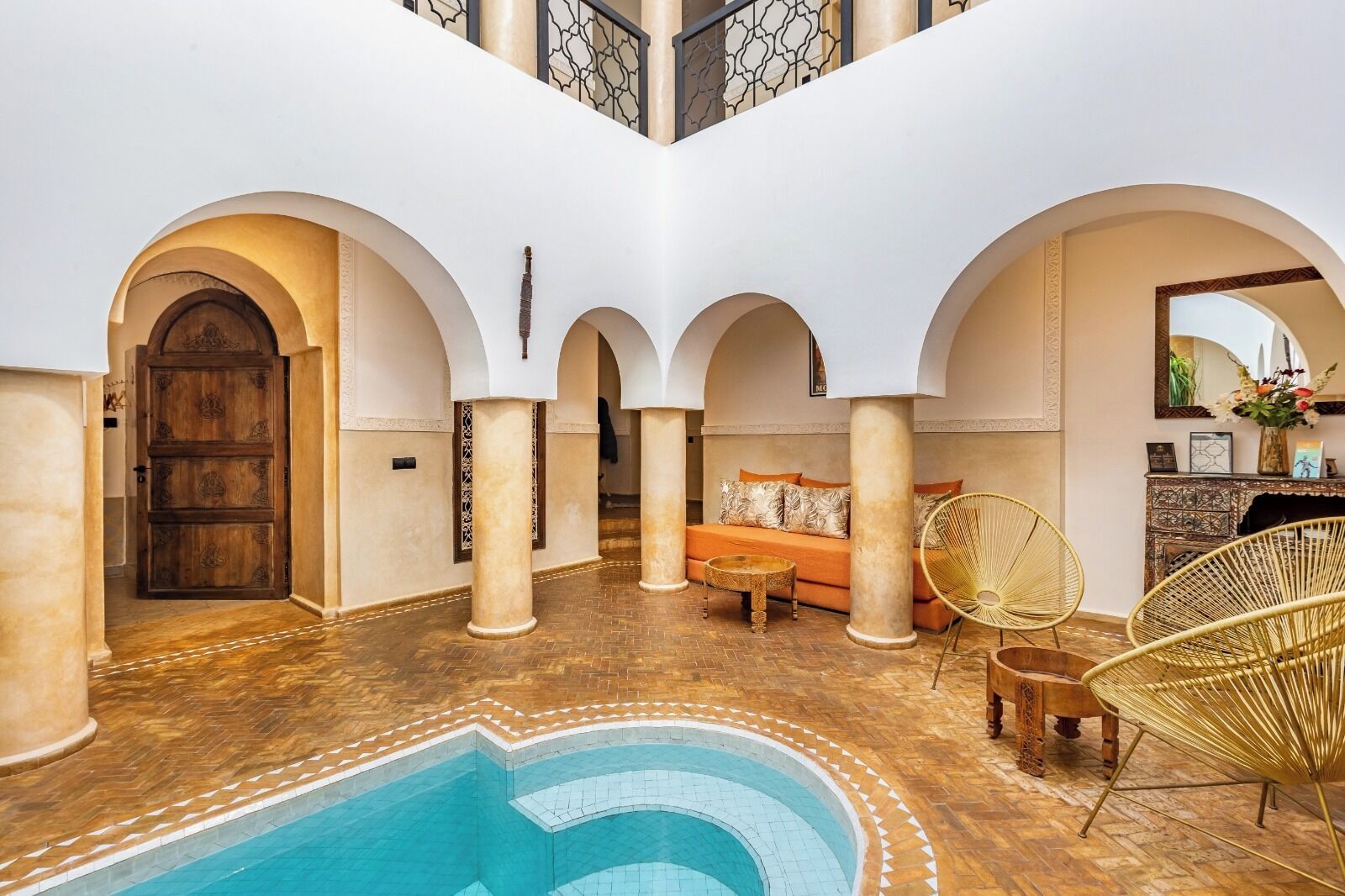 A pool area with a wooden door, a sofa, and wicker chairs.