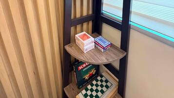 A corner with a wooden shelf holding a plant, a bowl, and a chessboard.