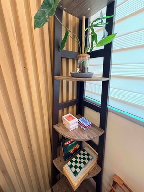 Una esquina con una estantería de madera que sostiene una planta, un cuenco y un tablero de ajedrez.