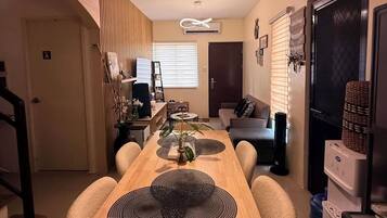 A modern kitchen with a wooden dining table, a hanging light fixture, and a refrigerator.