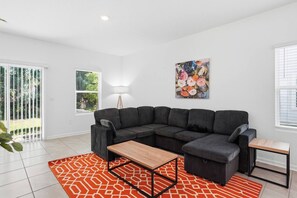 Een moderne woonkamer met een modulaire bank, een salontafel en een kleurrijk vloerkleed.