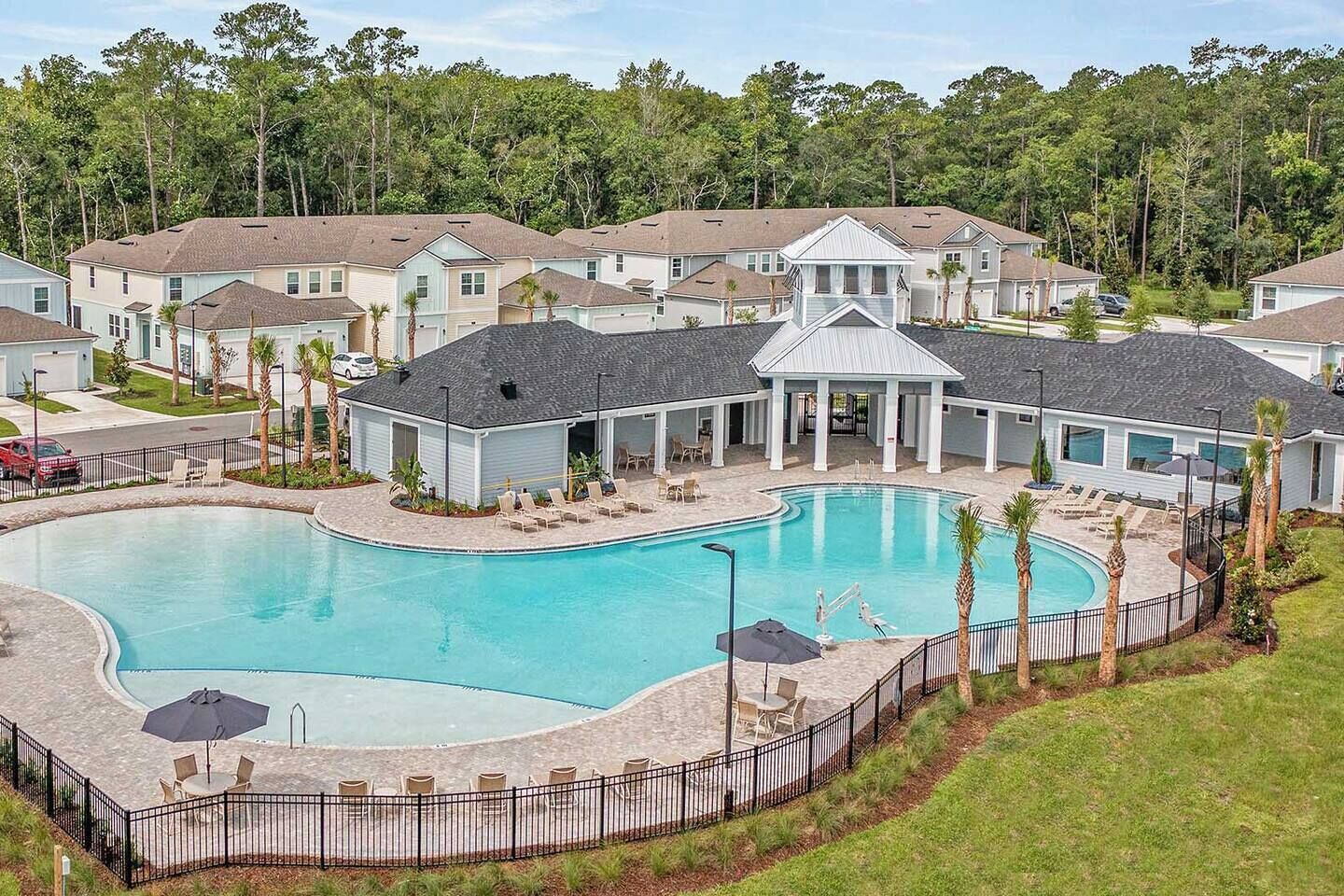 A residential area with a swimming pool, lounge chairs, and a covered patio.