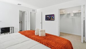 A hotel room with a bed, a desk, a TV mounted on the wall, and a closet. - Posh 3BR Townhome| Pool | Gym | Close to Beach (St. Augustine)