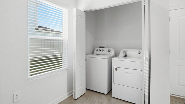 A laundry room with a washing machine and dryer, a window with blinds, and a door leading to another room. - Posh 3BR Townhome| Pool | Gym | Close to Beach (St. Augustine)