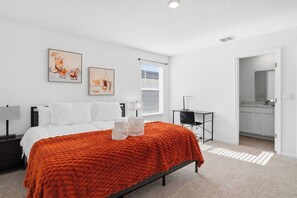 Een moderne slaapkamer met een bed, een bureau en kunst aan de muur.