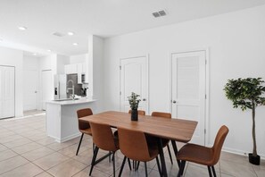A modern kitchen with white cabinets, a wooden dining table, and four chairs.