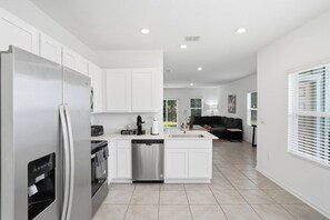 A modern kitchen with white cabinets, stainless steel appliances, and a central island.