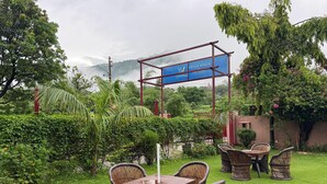 An outdoor seating area with wicker furniture and a blue sign. - Vella Vista Resort (dehradun)