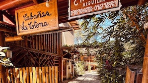 A wooden pathway leading to a building with signs reading 'Cabanas de la Lota' and 'Alquiler.'