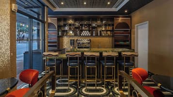 Un espace bar doté d’un comptoir en marbre, de plusieurs tabourets et d’une variété de bouteilles et de verres.