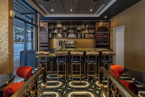 A bar area with a marble countertop, multiple stools, and a variety of bottles and glasses. - Aztec Hotel, San Antonio, A Tribute Portfolio Hotel (San Antonio)