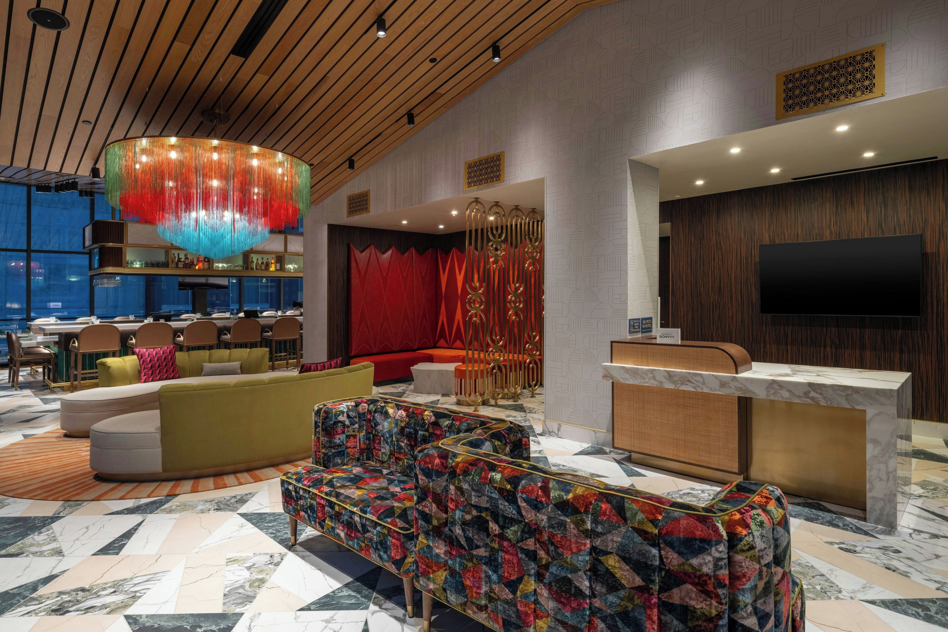 Un vestíbulo de hotel con mostrador de recepción, zona de estar y un bar.