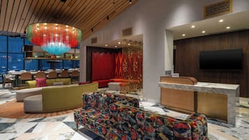 Un vestíbulo de hotel con mostrador de recepción, zona de estar y un bar.