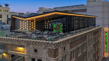 Un bâtiment moderne doté d'un bar sur le toit, avec des places assises en plein air et un panneau lumineux au néon.