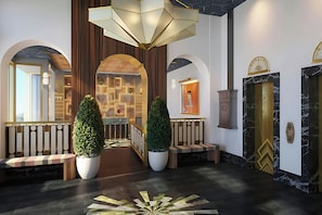 A lobby with a central staircase, potted plants, and a chandelier.