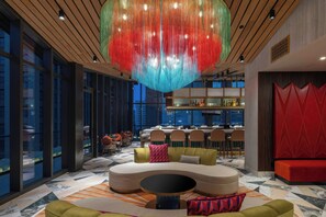 A modern interior with a large, colorful hanging light fixture, a seating area with a round table, and a bar with bottles. - Aztec Hotel, San Antonio, A Tribute Portfolio Hotel (San Antonio)