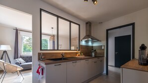 A modern kitchen with a large island, a built-in oven, and a stainless steel range hood.