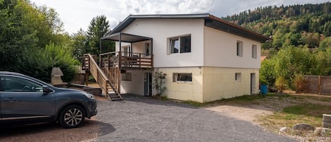 Une maison à deux étages avec un porche couvert et une voiture garée devant.