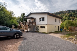 Une maison à deux étages avec un porche couvert et une voiture garée devant.