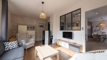 A modern living room with a sofa, coffee table, and a TV mounted on the wall.