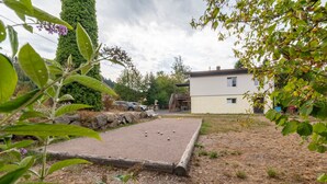 A courtyard with a croquet lawn, a stone wall, and a building in the background.