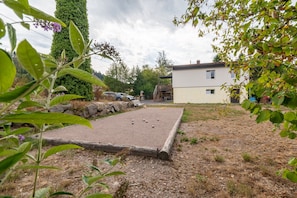 Un patio con césped para croquet, un muro de piedra y un edificio al fondo.