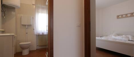 A bedroom with a bed, a bedside table, and a wall-mounted light fixture.