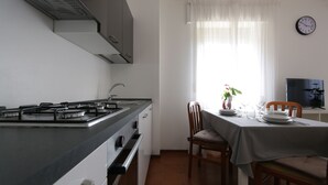 A modern kitchen with a gas stove, oven, and a dining area with a table set for two.