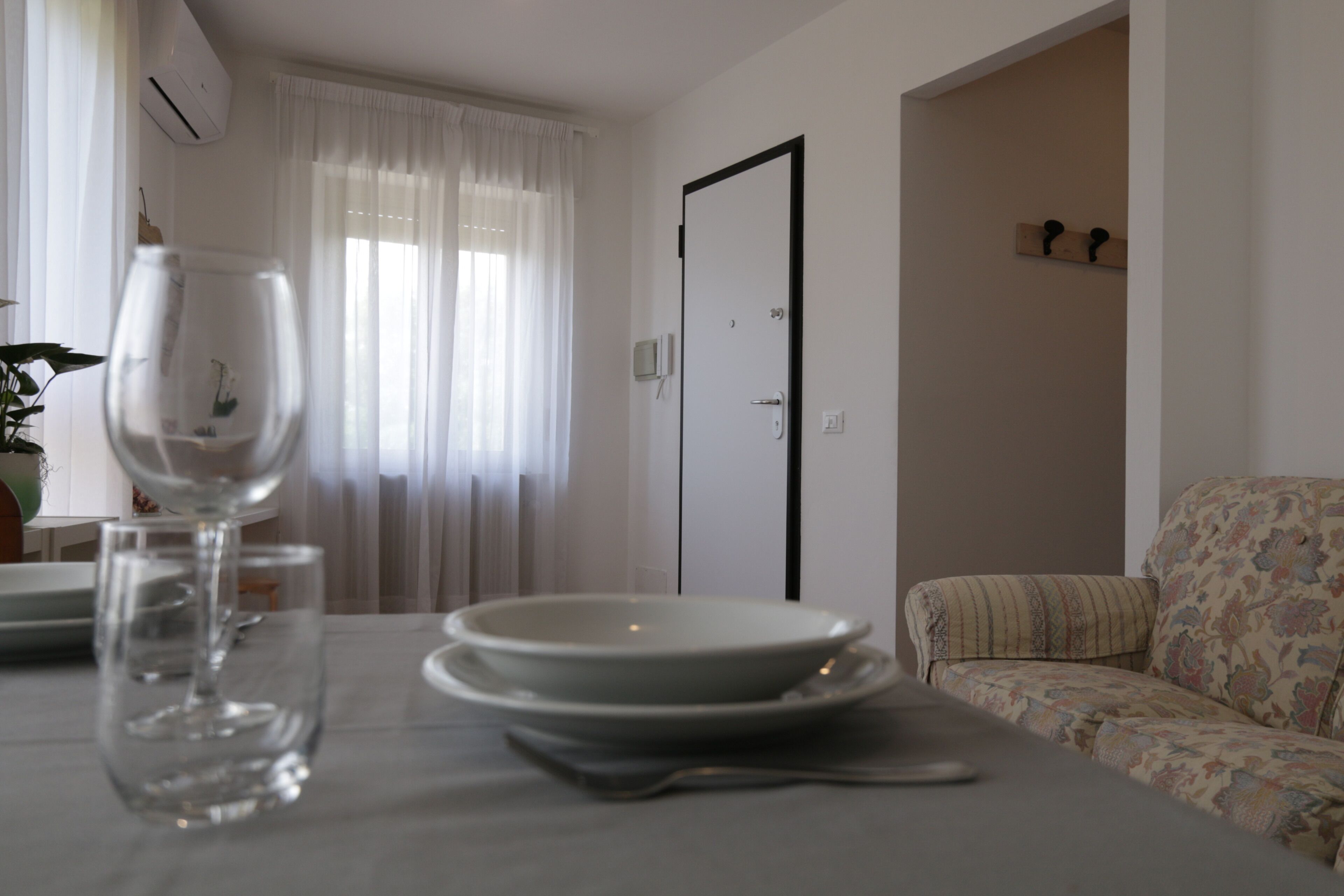 A dining area with a table set for two, a glass of water, and a door in the background.