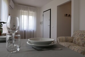 Un comedor con una mesa dispuesta para dos personas, un vaso de agua y una puerta al fondo.