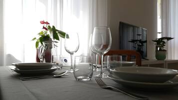 A dining table set with plates, cutlery, and wine glasses, with a vase of flowers and a pitcher of water.