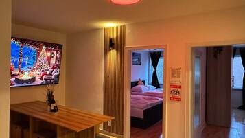 Ein Hotelzimmer mit einem Holztisch, einem Fernseher, der eine Weihnachtsszene zeigt, einem Bett mit rosa Bettwäsche und einem Schild mit der Aufschrift 'Keine Party'.