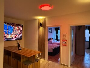 Ein Hotelzimmer mit einem Holztisch, einem Fernseher, der eine Weihnachtsszene zeigt, einem Bett mit rosa Bettwäsche und einem Schild mit der Aufschrift 'Keine Party'.