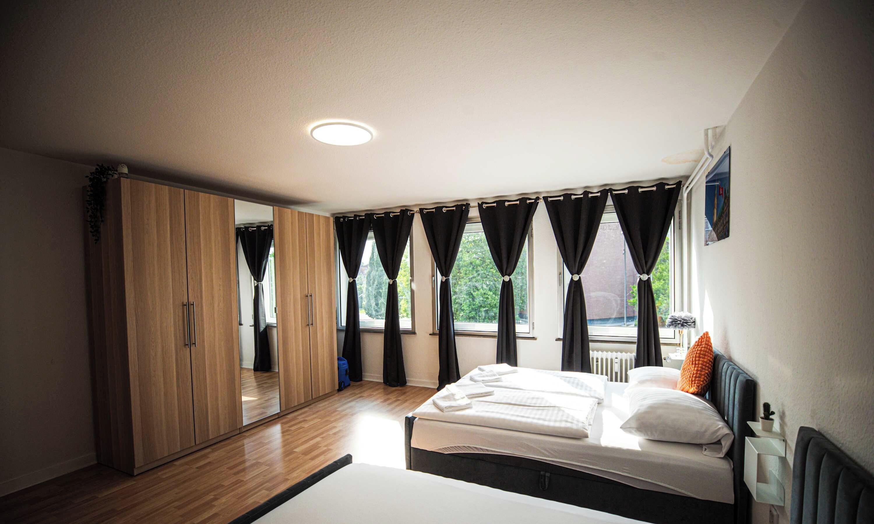 Ein Schlafzimmer mit einem Bett, einem Kleiderschrank und einem Fenster mit Vorhängen.