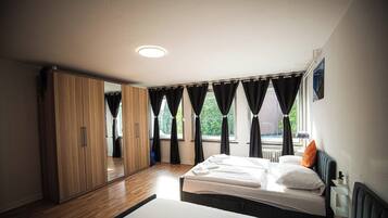 Ein Schlafzimmer mit einem Bett, einem Kleiderschrank und einem Fenster mit Vorhängen.