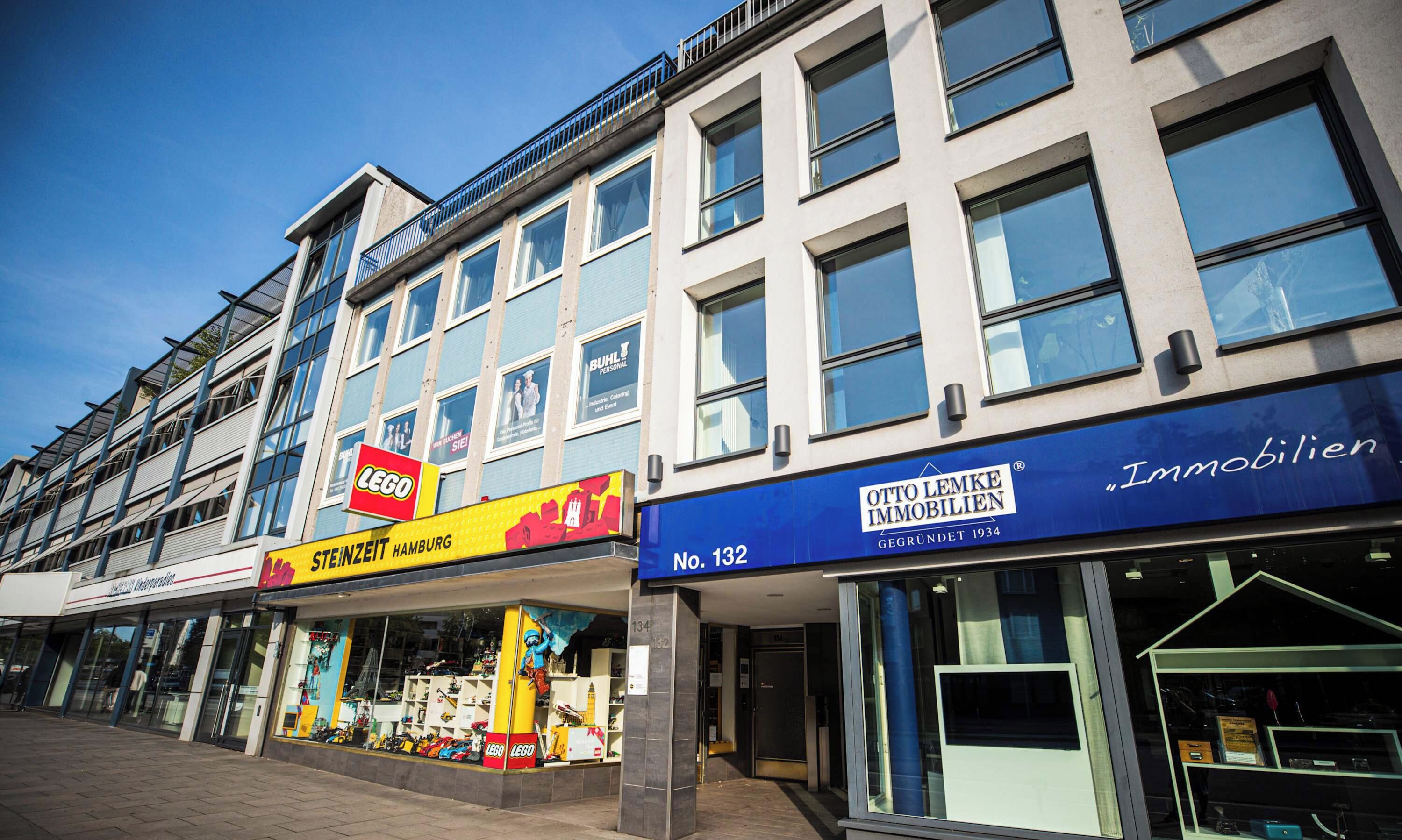 Ein Geschäftsgebäude mit Schaufenstern, darunter ein LEGO-Laden, Steinzeit Hamburg und Otto Lemke Immobilien.