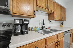 A kitchen with wooden cabinets, a coffee maker, a sink, and a dishwasher.