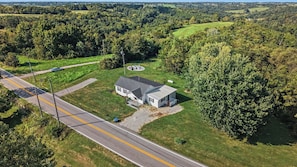 A house with a large front lawn, a circular patio, and a road with a speed limit sign.