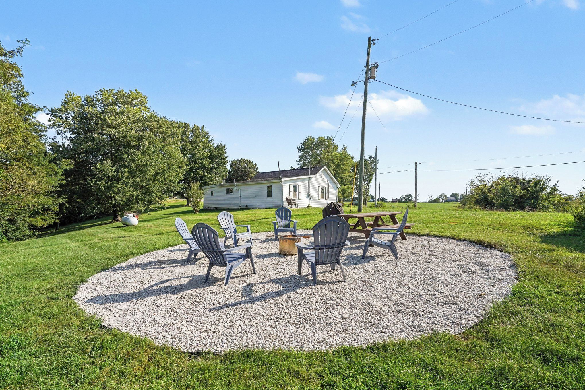 A house with a gravel patio, outdoor seating, and a fire pit.