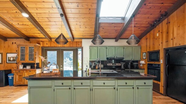 A spacious kitchen with a large island, wooden cabinetry, and a skylight.