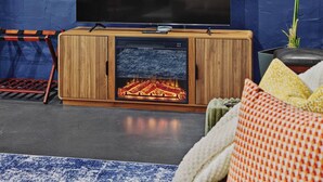 A modern living room with a built-in fireplace, a television, and a wooden cabinet.