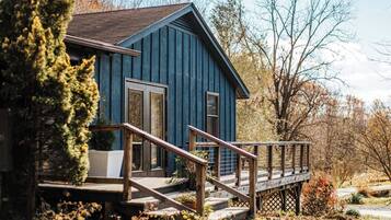 Une maison en bois bleue avec un escalier en bois menant à une terrasse.