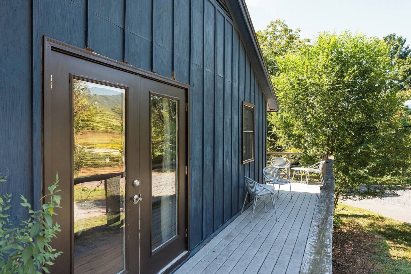 A wooden deck with a glass door and a small outdoor seating area.