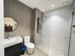 Une salle de bain moderne avec une douche à parois de verre, un lavabo blanc et des toilettes.