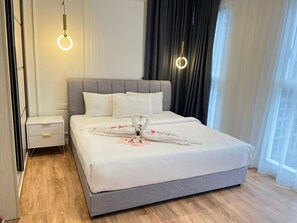 Ein Hotelzimmer mit einem großen Bett, Nachttischen und einem Fenster mit Vorhängen.
