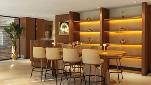 A modern dining area with a round table and six chairs, a decorative plant, and a wall with shelves containing various items.