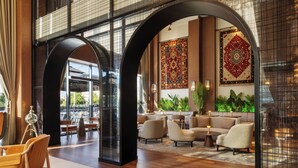 A spacious lobby with high ceilings, large windows, and a seating area with sofas and tables.
