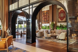 A spacious lobby with high ceilings, large windows, and a seating area with sofas and tables.