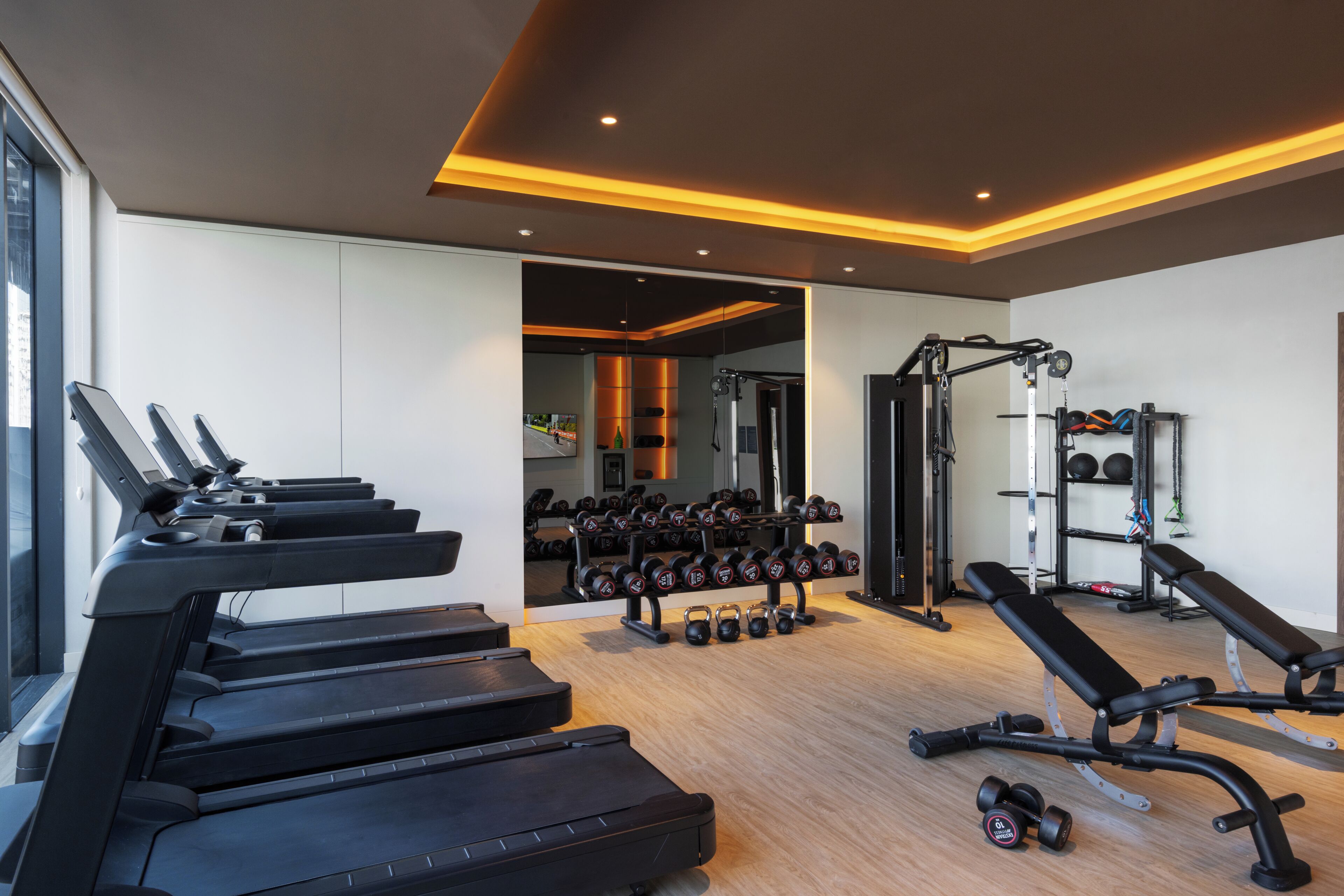 Un gimnasio con cintas de correr, mancuernas y máquinas de pesas.