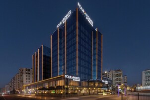 Un hotel de varios pisos con señalización llamativa, un restaurante a nivel de calle y una fachada bien iluminada.